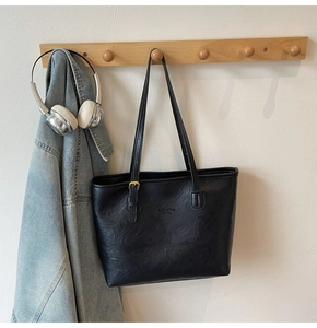 Detail of black leather tote bag with gold buckle and fashion bag New York embossing
