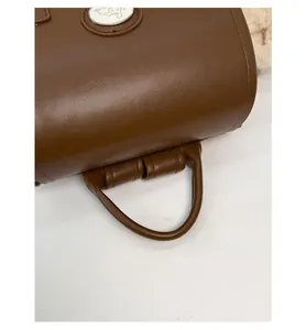 Detail of the brown leather top handle with thick cylindrical stitching and soft texture
