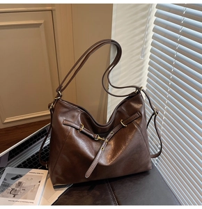 Detail of a large dark brown tote bag with gold ring and textured leather texture