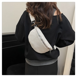 Detail of cream corduroy crescent bag featuring wide jacquard strap and silver metal zipper