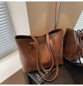 Detail of a brown tote bag featuring Fashion Bag New York logo and golden hardware