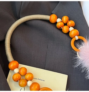 Détail macro d'un pompon en fausse fourrure rose et perles oranges sur une anse de sac