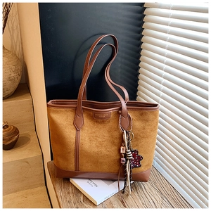 Dettaglio borsa tote in camoscio cammello con finiture in pelle e charm a forma di orso