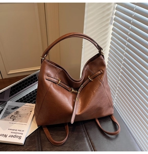 Close-up of brown matte PU leather texture and vintage gold metal buckles on a tote bag