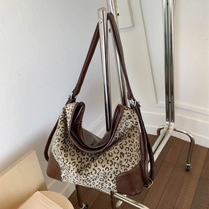 Detail of leopard print tote bag with brown leather trim on a metal display stand