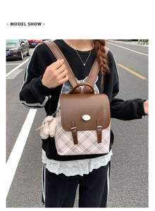 Outdoor model show of casual checkered backpack with brown leather flap and pink charm
