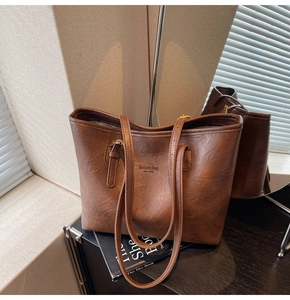 Close-up of brown tote bag showing its vintage leather texture and gold buckle detail