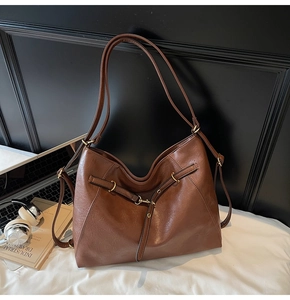 Detail of vintage brown leather tote bag with metallic buckle and smooth texture finish