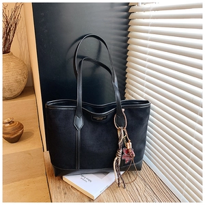 Dettaglio borsa tote in pelle nera con logo metallico e ciondolo a forma di orso
