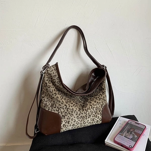 Detail showing leopard print tote with reinforced leather corners and long shoulder strap