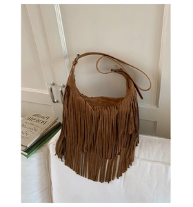Dettaglio delle lunghe frange e della trama in camoscio di una borsa boho marrone a tracolla