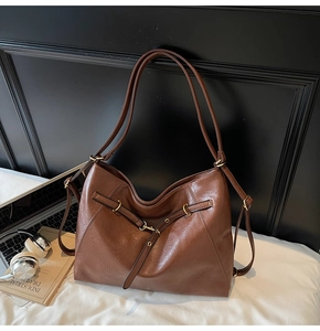 Detail of dark brown large tote bag with lychee texture and golden hardware