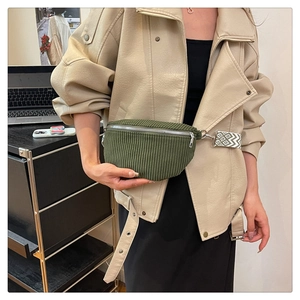 Detail of dark green corduroy waist bag with geometric patterned wide strap on a model
