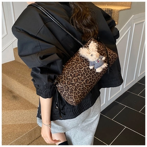Vista posterior de un bolso tote con estampado de leopardo y colgante de conejo en modelo