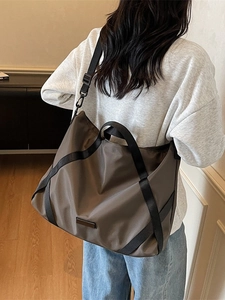 Große dunkelbraune Reisetasche mit Schultergurt getragen von einem Modell