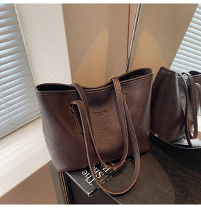 Detail of deep brown faux leather tote bag with New York text in soft shadow lighting