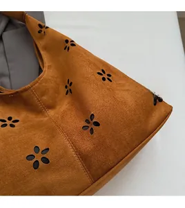 Detailed view of caramel brown suede tote bag with laser-cut floral hollow patterns