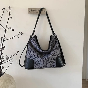 Close-up of leopard print hobo bag hanging on a vintage hook against a white wall