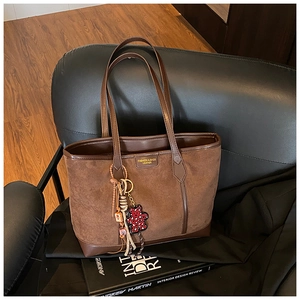 Detail of vintage matte brown tote bag with leather tag, leopard bear and tassel charm