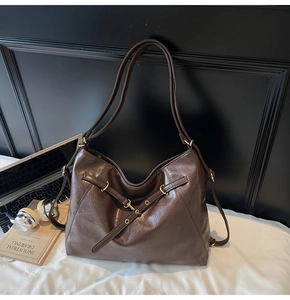 Detail of dark brown faux leather tote bag with metallic eyelets on white bedding