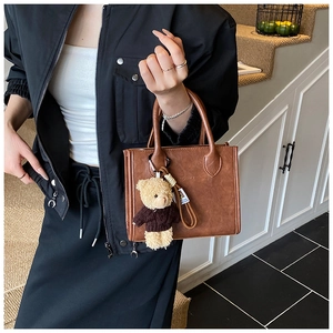 Detailed close-up of brown vintage crossbody bag with cute plush bear charm accessory
