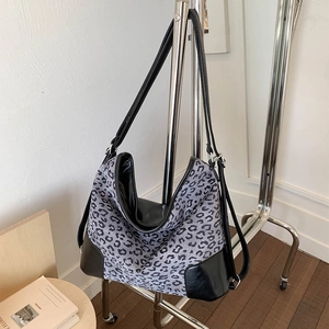 Close-up of leopard print tote bag with black faux leather base and adjustable strap