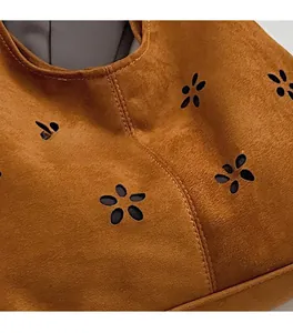 Macro shot of dark brown suede tote with laser-cut floral patterns and stitching