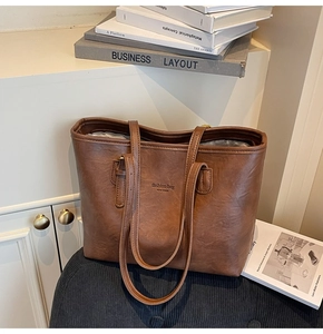 Detail of a brown textured faux leather tote bag with New York text and zipper closure