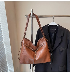 Detailed view of dark brown retro leather texture and metal buckle on large tote bag