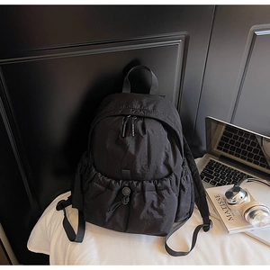 Detail of black nylon backpack featuring drawstring pocket and matte waterproof fabric