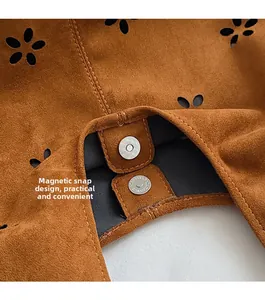 Close-up of magnetic snap closure on a brown suede tote bag with floral cutouts