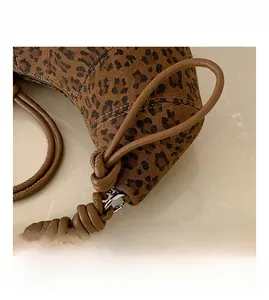 Detail of leopard print bag showing woven texture, brown leather knot and metal ring
