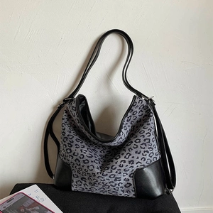 Close-up of grey leopard canvas tote with black leather corners and slim straps