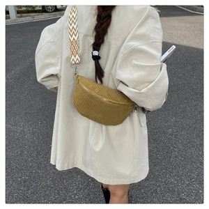 Detail of corduroy crossbody bag with geometric wide strap shown in outdoor setting