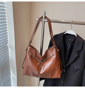 Detailed view of caramel brown PU tote bag with cross-strap design and gold ring hardware