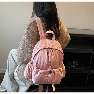 Detailed side view of a soft pink nylon backpack with drawstring pocket and zip closure