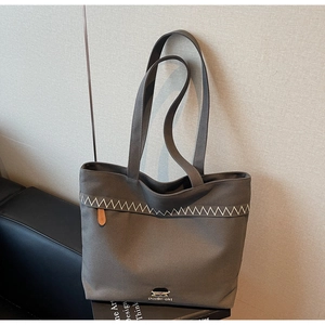 Detail shot of a coffee canvas tote bag with embroidered Poelle-girl logo and wavy stitching