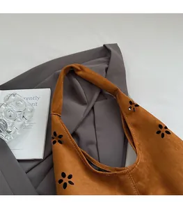 Detail of laser-cut floral patterns on caramel suede tote bag with wide shoulder strap