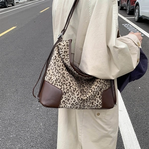 Close-up of leopard print tote bag with brown leather accents and adjustable strap