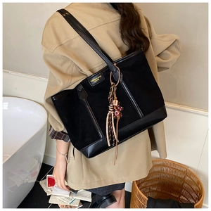 Detail of black matte tote bag featuring leather patch and cute bear tassel charm