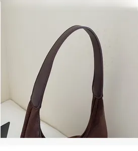 Macro shot of the durable wide shoulder strap on a brown suede shoulder bag