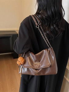 Dark brown pleated underarm bag with gold chain strap and teddy dog plush charm