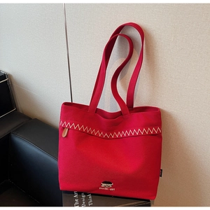 Close-up of red canvas tote bag with white zigzag embroidery and cartoon portrait