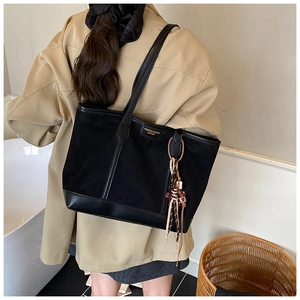 Detail view of large black matte tote bag with teddy bear charm and gold metal plate