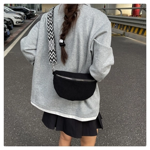 Detail of black corduroy saddle bag with a geometric pattern wide woven strap
