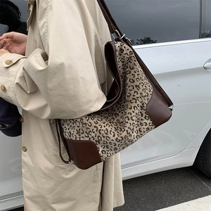 Detail of leopard print canvas tote bag with brown leather trim and metal buckle