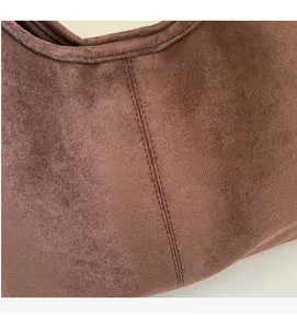 Detailed macro view of the brown suede fabric and premium double stitching on the handbag
