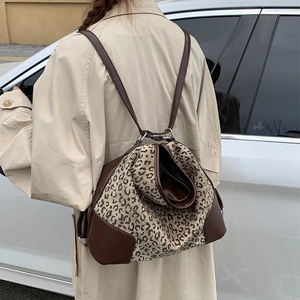 Outdoor shot of a leopard print tote bag with brown leather trim worn as a shoulder bag