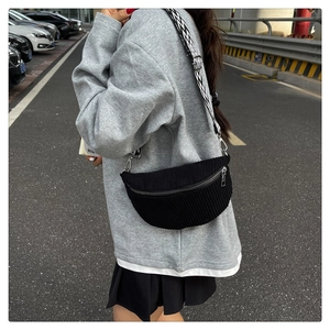 Detail of black corduroy crescent bag with geometric wide strap and silver hardware