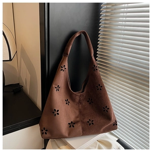 Detail of laser-cut floral pattern on a brown suede tote bag with soft shadow lighting